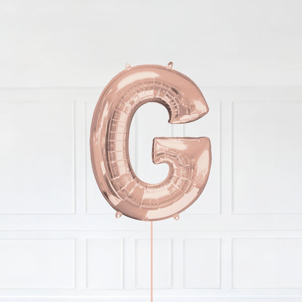 Letter G Foil Balloon Inflated With Helium, Rose Gold Color Letter G with Balloon String and Balloon Weight.