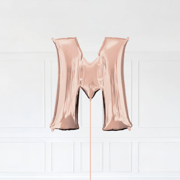 Letter M Foil Balloon Inflated With Helium, Rose Gold Color Letter M with Balloon String and Balloon Weight.