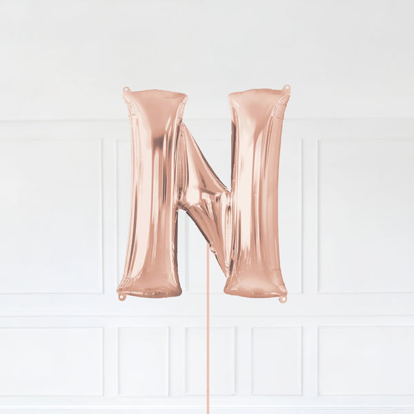 Letter N Foil Balloon Inflated With Helium, Rose Gold Color Letter N with Balloon String and Balloon Weight.